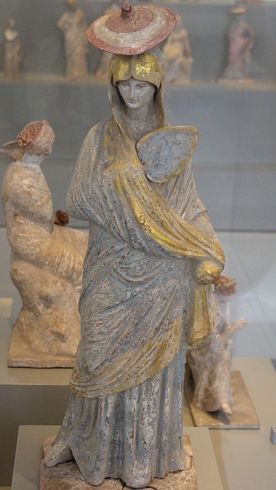 Lady with blue and gilt garment, imatio, chitone, pointed hat (tholia) and fan, from Tanagro 325-300 BC.