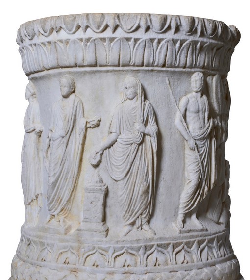 A sacrificial altar originally placed in the forum of the Roman city of Abellinum, this piece is crafted from Greek marble and consists of a circular body entirely decorated with a figurative frieze set between two cornices. The focal point of the decoration is a sacrificial scene framed by two groups of figures, one on the right and the other on the left. There are two main interpretations of this scene and the dating of the altar.
