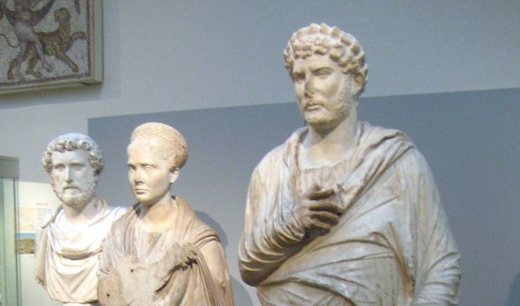 On right, Roman emperor Hadrian in Greek dress offers a sprig of laurel to Apollo. From the temple of Apollo at Cyrene. According to Tracey Sweek, the head does not belong to the  body - London, British Museum